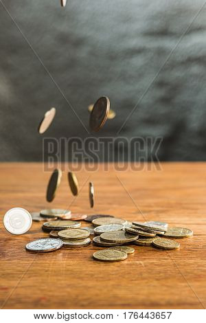 The silver and golden coins and falling coins on wooden table background