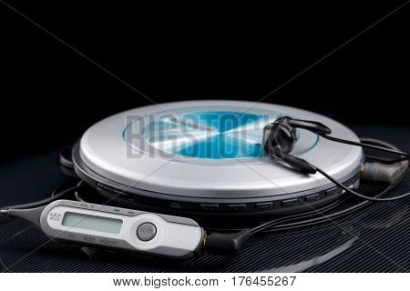 personal cd player with remote control and portable audio earphones on black background