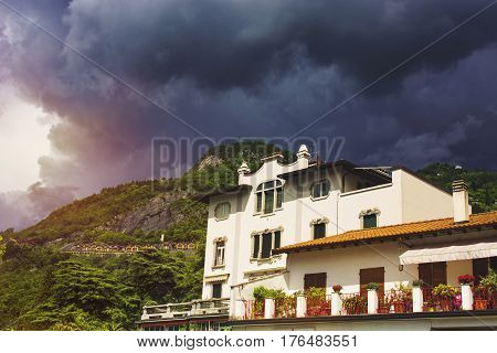 Beautiful cityscape of italian Varenna with building green mountain and dramatic cloudy sky before the rain
