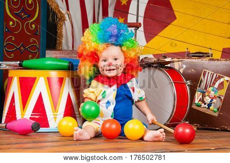 Little baby clown with red nose multi-colored wig in with balls.