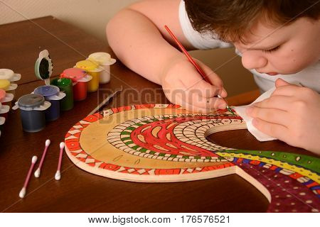 The child paints the colors of the wood