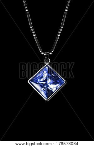 Blue sapphire pendant on silver chain isolated over black