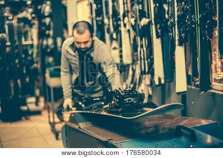 Snowboard Tuning And Reapairs. Winter Shop Worker Doing Base Repair
