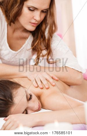 Young masseur doing back massage carefully. Looking down at woman back concentrated. Spa massage