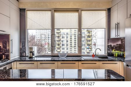 Contemporary modern black colored kitchen with fitted appliances and breakfast bar, window view on buildings at chisinau albisoara street, chisinau, moldova