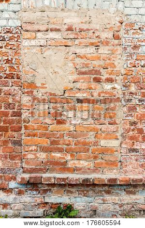 Old gungy red brick wall with bricked up window