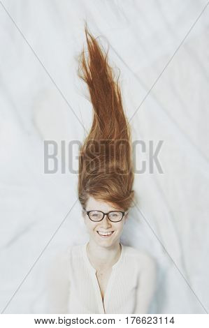 A girl in glasses with long blond hair lies and smiles