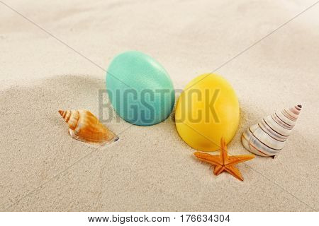 Colorful Easter eggs with seashells on sand