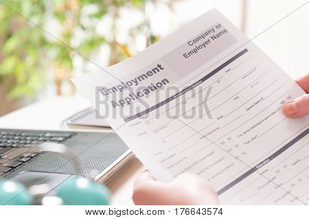 Blank employment application form in hands on a desk