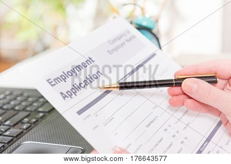 Blank employment application form in hands on a desk