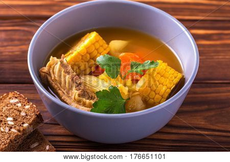 Puchero Soup With Corn And Parsley On Wooden Table