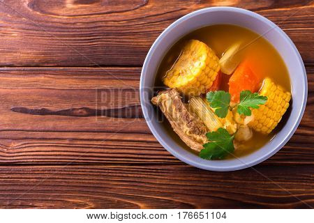 Puchero Soup With Corn And Parsley On Wooden Table