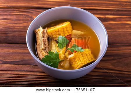 Puchero Soup With Corn And Parsley On Wooden Table