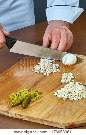 Cook cuts champignons for making a jelly chicken collection of culinary recipes