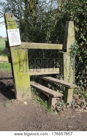 An English stile in the countryside which are steps or rungs by which a person may pass over a fence that remains a barrier to sheep or cattle.Stiles are often built in rural areas