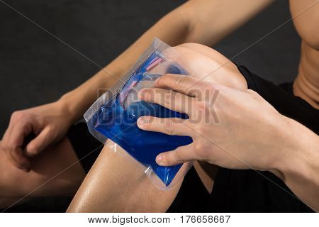 Close-up Of A Person Applying Ice bag On An Injured Knee In The Gym