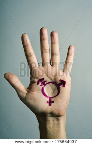 closeup of a transgender symbol painted in the palm of the hand of a young caucasian person