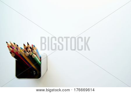 A lot of colored pencils inside a tin can on the white background.