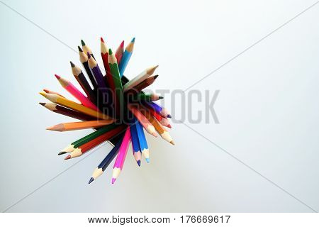 A lot of colored pencils inside a tin can on the white background.