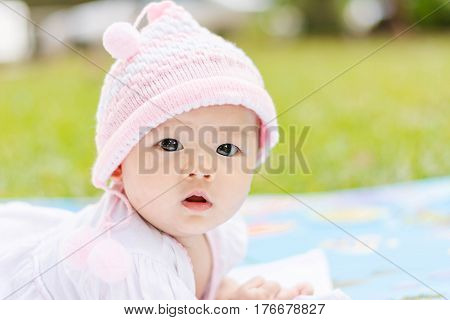 Cute Asian Baby Lie Prone On Ground At Park