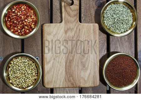 Bowls of spices containing mustard seeds fennel seeds coriander seeds red pepper flakes on a wooden background sith copy space.Top view.