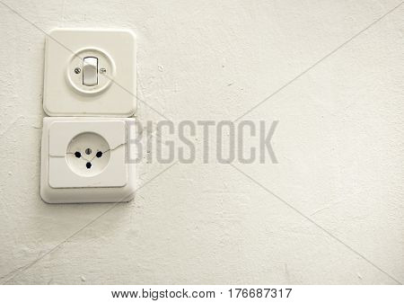 Old vintage switch and socket on a white plastered wall