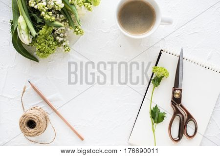 Feminine flatlay with flowers and ccoffee on white textured tabletop, design ready arrangement