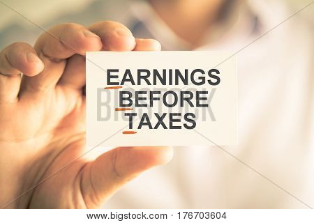 Businessman Holding Card With Ebt Earnings Before Taxes Acronym Text