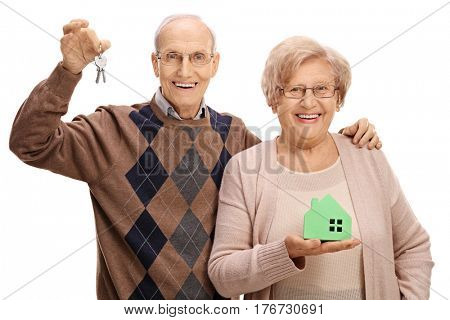 Joyful seniors with a pair of keys and a model house isolated on white background
