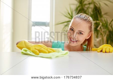 people, housework and housekeeping concept - happy woman cleaning table at home