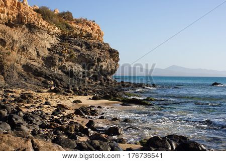 Black rocks of Costa Calma beach. Blue sea line. Playa Barca, Fuerteventura, Canary islands, Spain. Istmo de la pared view
