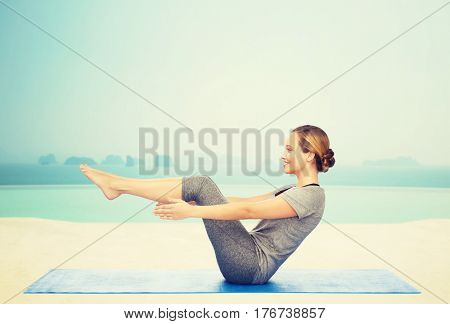 fitness, sport, people and healthy lifestyle concept - woman making yoga in half-boat pose on mat over infinity edge pool at hotel resort background