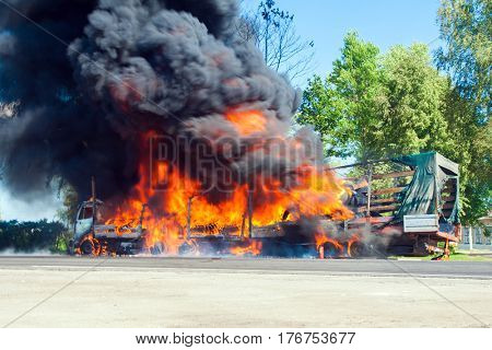 truck in fire with black smoke on the road