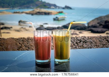 Two glasses with cocktails in glasses on the background of sea and sky. Coffee cocktail and a strawberry smoothie for Breakfast.