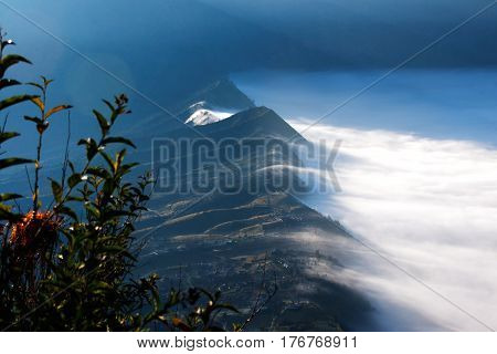 White clouds of mist covering village seen at a distance in the morning from Mount Penanjakan at the Tengger Semeru National Park in East Java Indonesia.