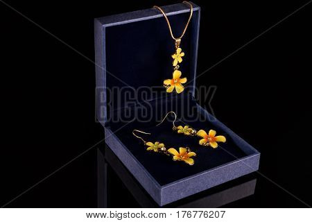 Chain with pendant and earrings in a blue box on a black background