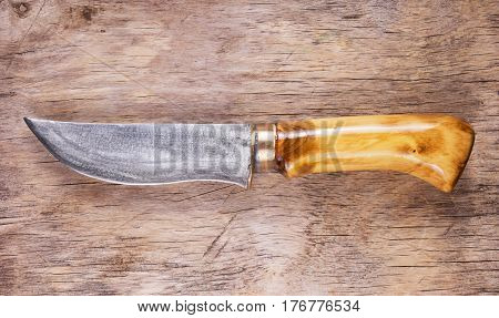 Knife handmade from steel and wood handle and brass quince. Stylish knife on old wooden background.