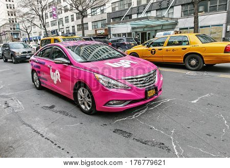 New York March 11 2017: A pink car with Lyft logo is driving along 14th street in Manhattan. Lyft offers a convenient way to hire a ride using a smartphone.