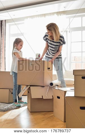 Mother and daughter packing cardboard boxes at home
