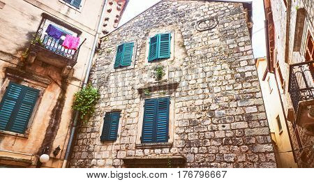 Kotor narrow small streets of historical old town. House drying linen bright sun blind old stone. Authentic structures. No body tourists.
