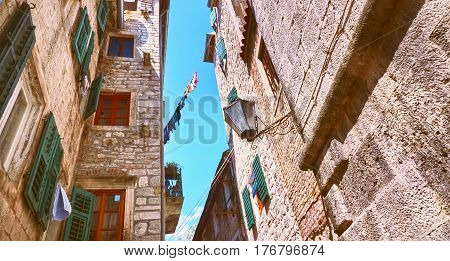 Kotor narrow small streets of historical old town. House drying linen bright sun blind old stone. Authentic structures. No body tourists.