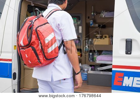 male nurse carry nursing bag on his back standing beside ambulance prepare for helping people