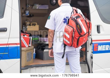 male nurse carry nursing bag on his back standing beside ambulance prepare for helping people