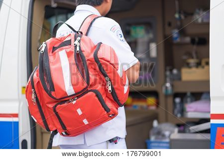 male nurse carry nursing bag on his back standing beside ambulance prepare for helping people