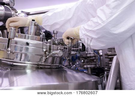 A Man Opens A Chemical Reactor. Rector Of The Pharmaceutical Industry. The Man Closes The Reactor. P