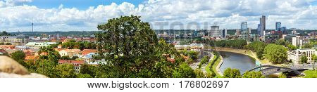 Panorama of Vilnius from top of mountain of Gediminas Tower. Red rooftops of old town & modern business building of glass and concrete. River Vilia parts of historic and business districts. Lithuania
