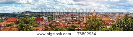 Panorama of Vilnius from top of mountain of Gediminas Tower. View of red rooftops of old town spires and towers of cathedrals & churches. River Vilia parts of historic & business districts. Lithuania