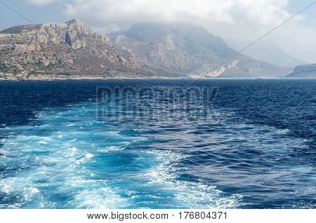 The rocky coast of the Mediterranean sea against the blue sky and clouds.