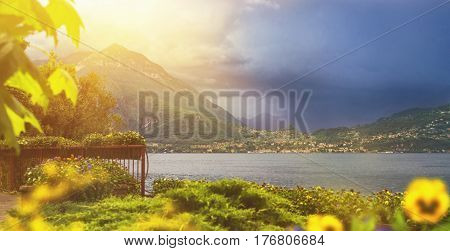 Beautiful toned panoramic waterscape of coastline of italian Varenna city with mountains on background leaf on foreground and dramatic sky before the rain