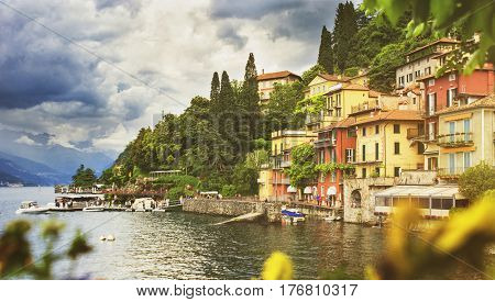 Beautiful cityscape with a Como lake coastline of italian Varenna city with colorful building big trees and dramatic sky before the rain